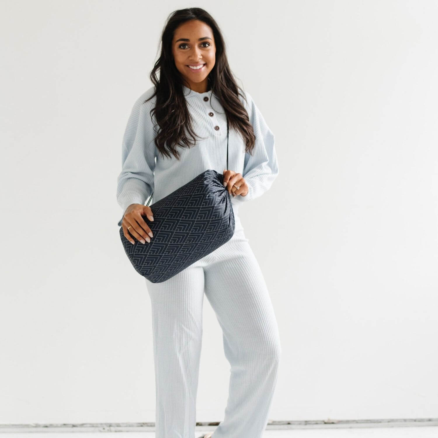Woman holding a black quilted handbag against a white background