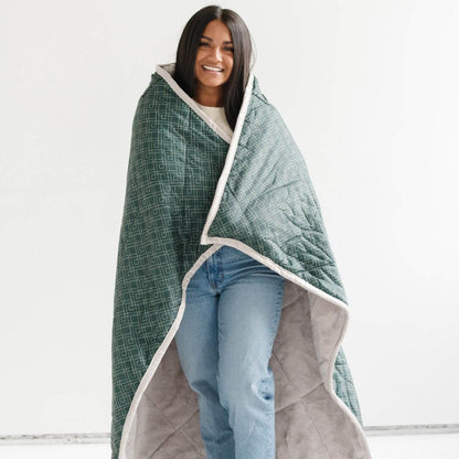 Woman wrapped in Saranoni Outdoor Blanket against a white background