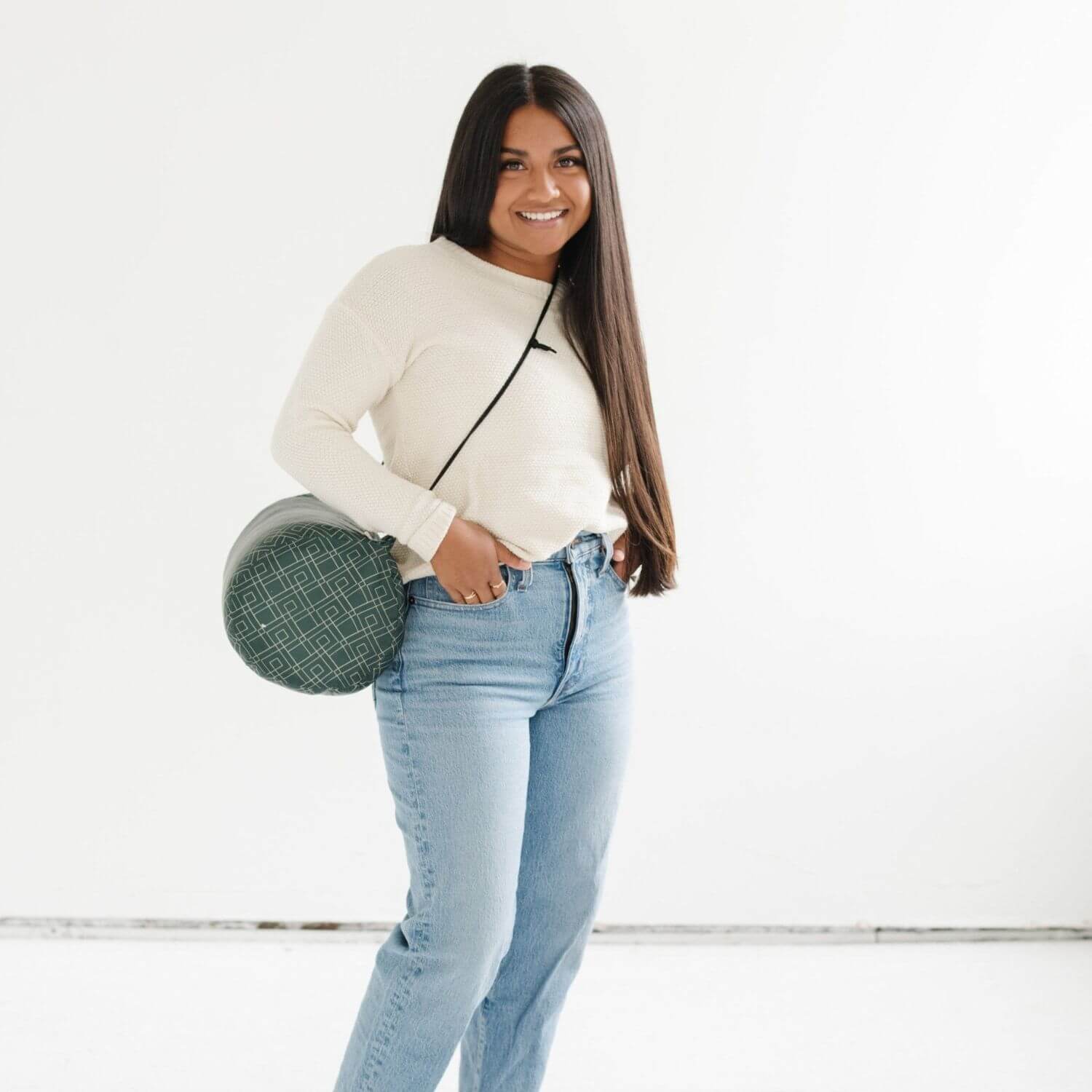 Woman holding a green circular bag against a white background