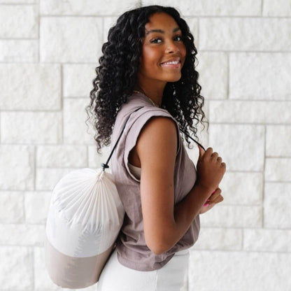 Woman holding a white drawstring bag against a light tiled wall