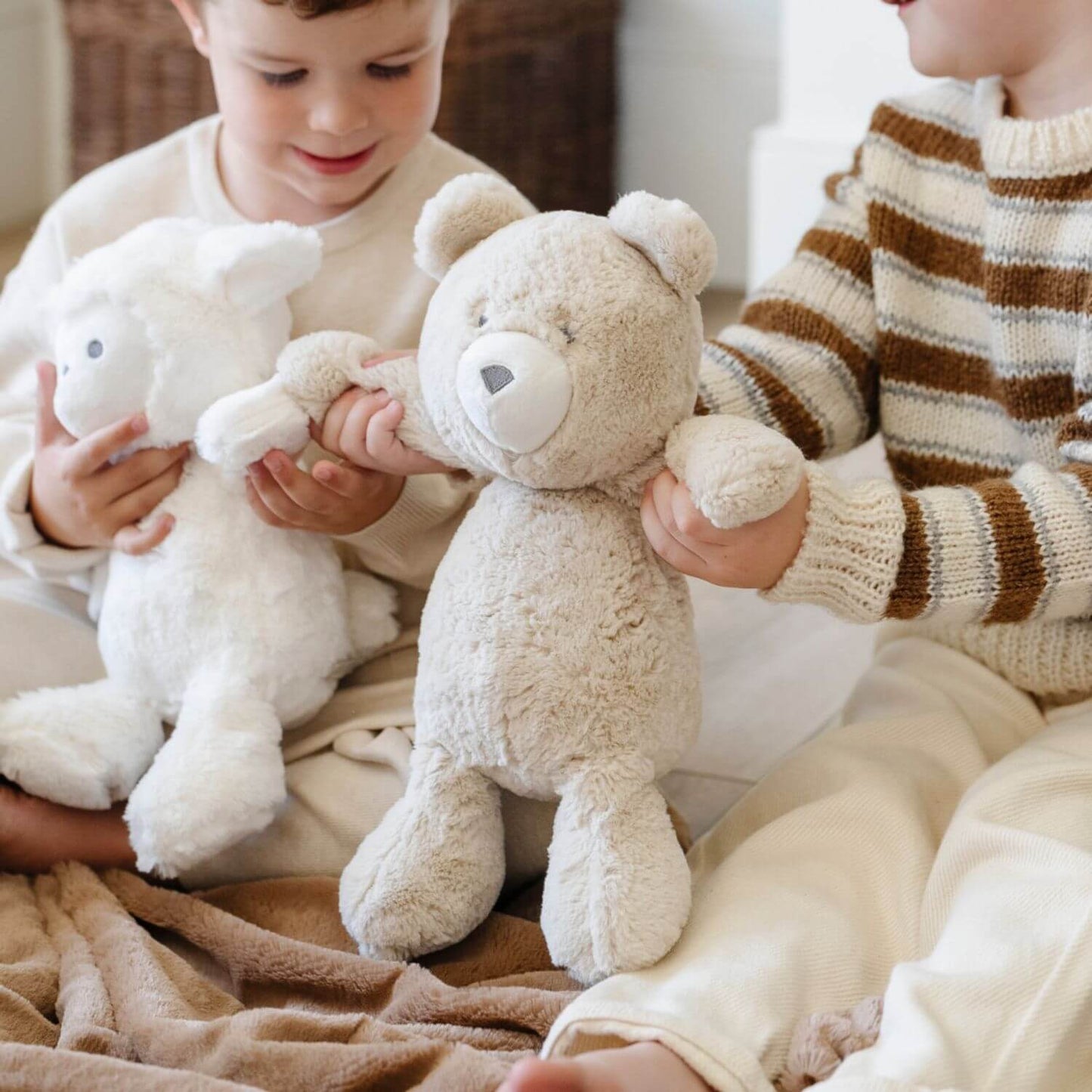 Two children holding Saranoni Stuffed Animals on a couch