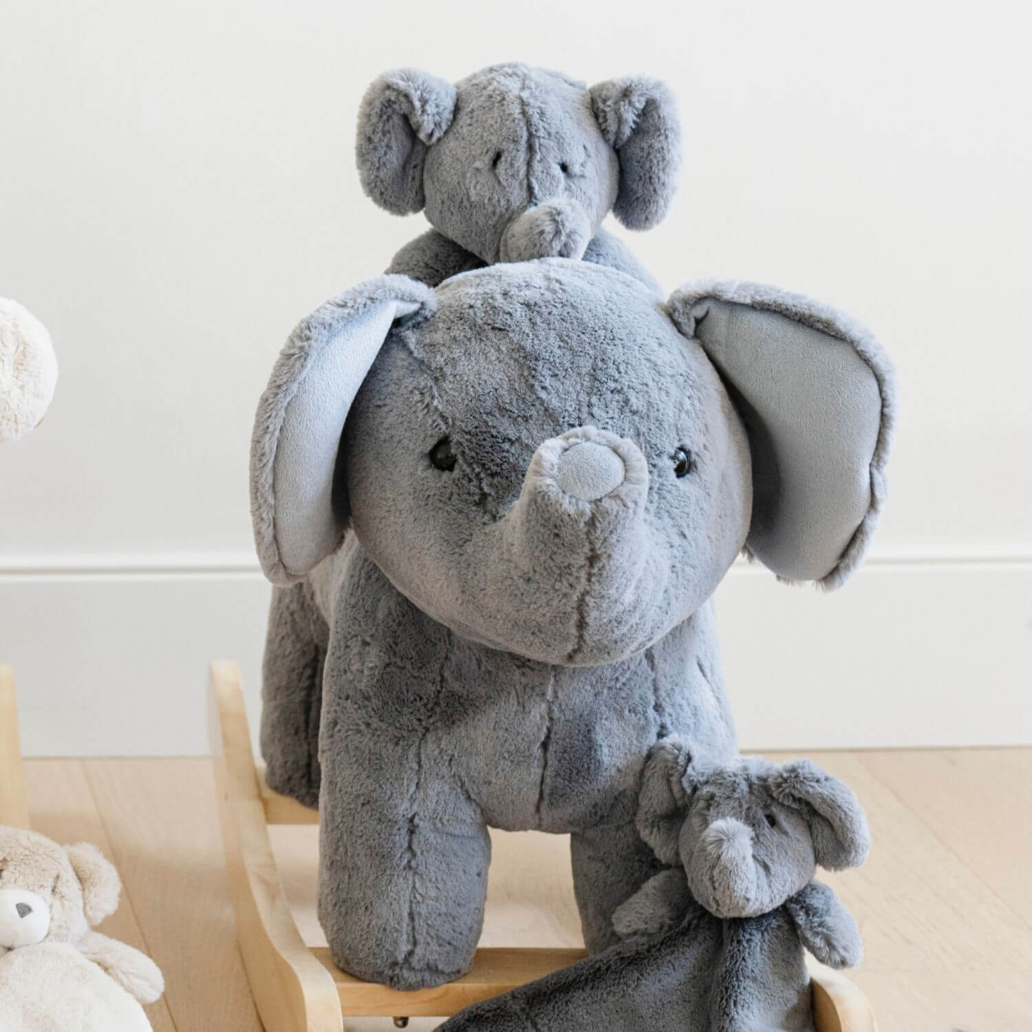 Two gray plush elephants stacked on top of each other with a white background