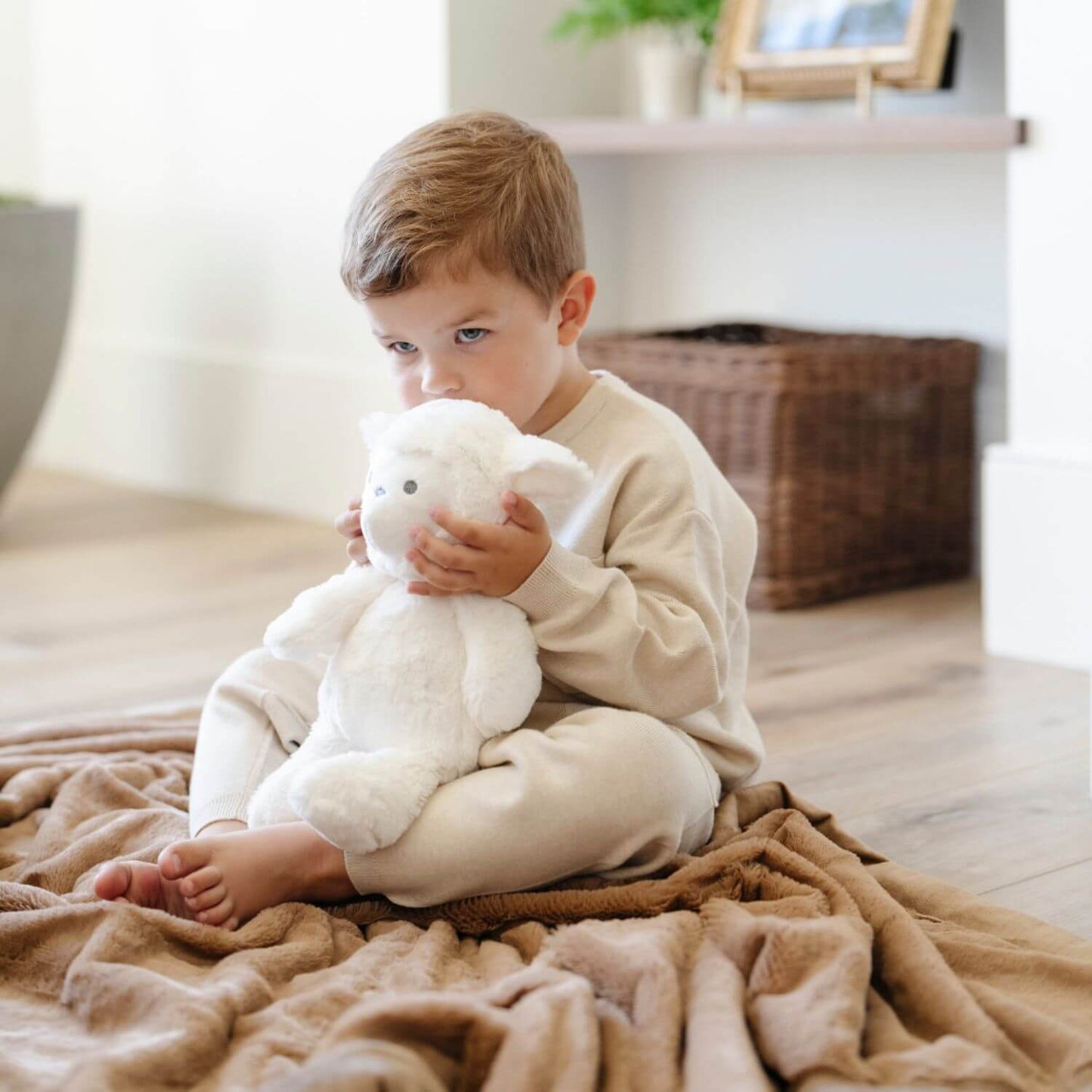 Child holding Saranoni Stuffed Animal lamb in a cozy indoor setting