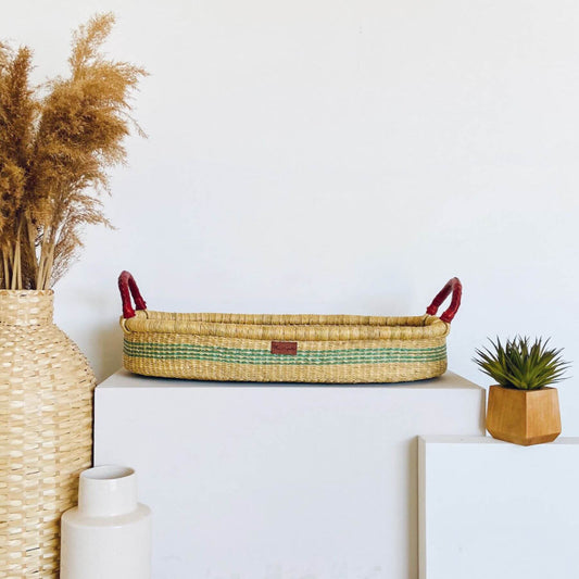 Plum+Sparrow Seabrook Changing Basket on a white surface, surrounded by decorative items.