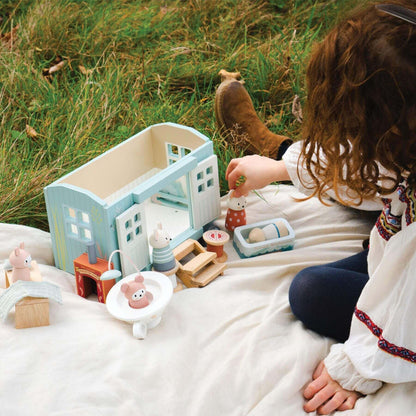 Child playing with tTender Leaf Secret Meadow Shepherd’s Hut on a blanket outdoors