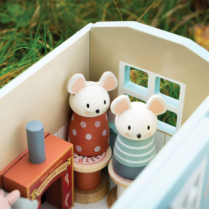 Wooden toy mice in a small house with a grassy background
