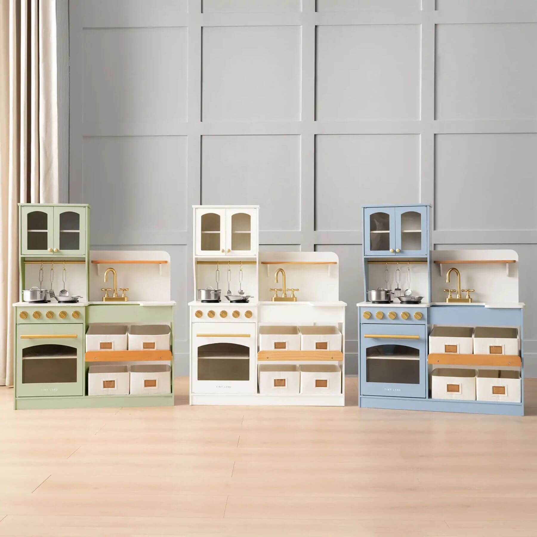 Set of Tiny Land® Serenity Play Kitchen on a wooden floor with a gray paneled wall background.