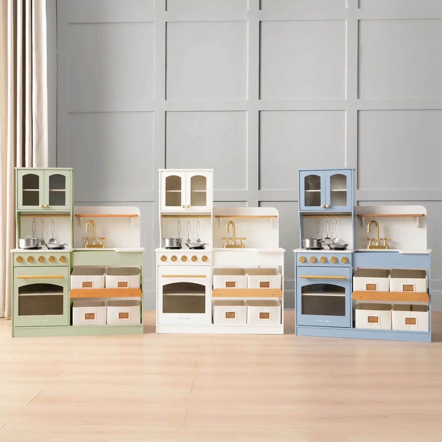 Set of Tiny Land® Serenity Play Kitchen on a wooden floor with a gray paneled wall background.