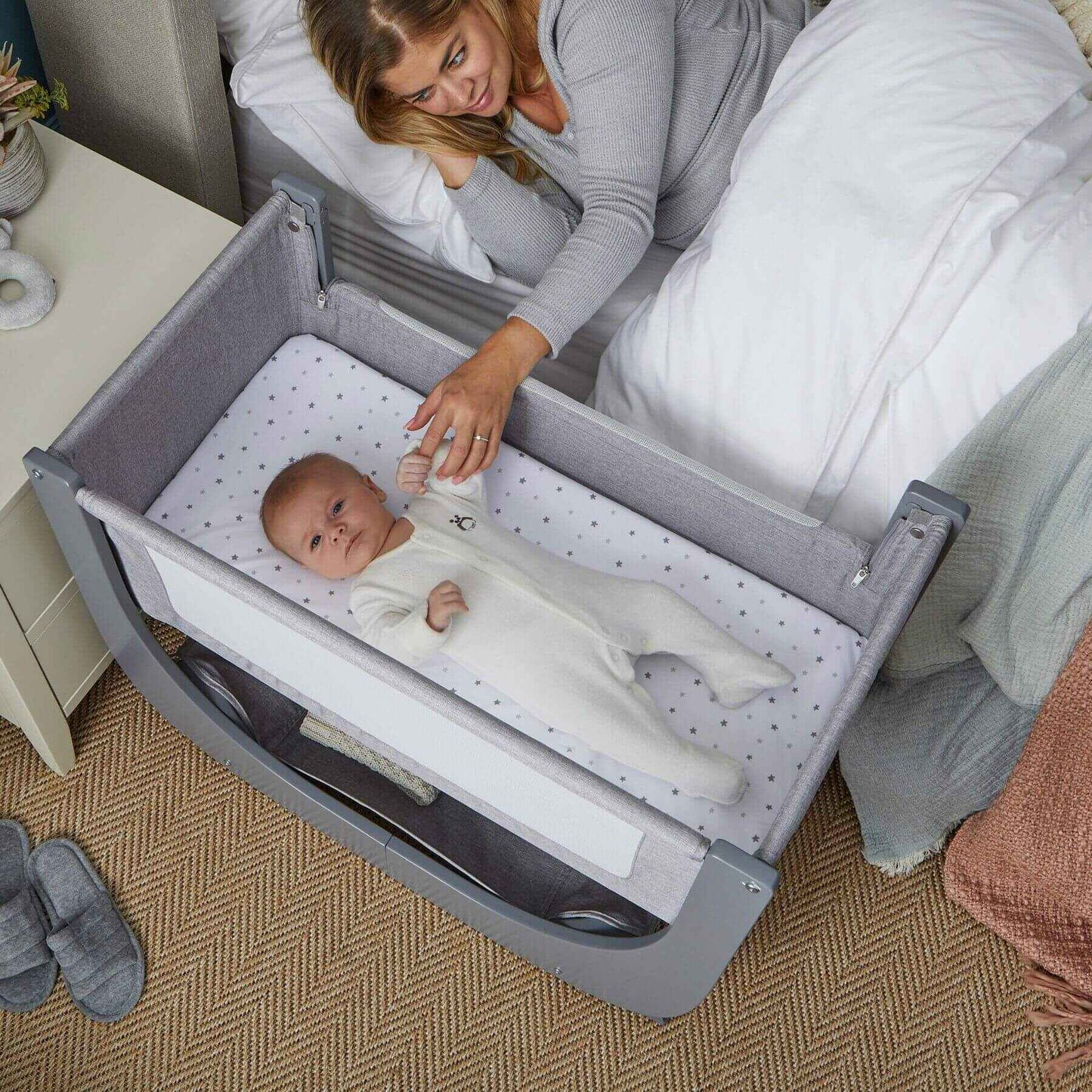 Baby in a crib with a woman in the background