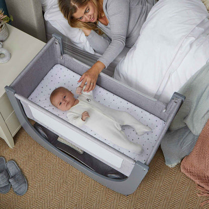 Baby in a crib with a woman in the background