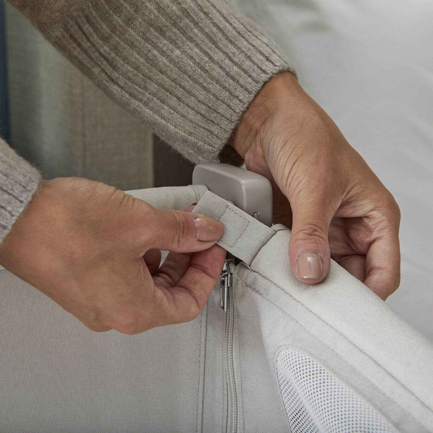 Person adjusting a zipper on Shnuggle Air Lite Bedside Bassinet