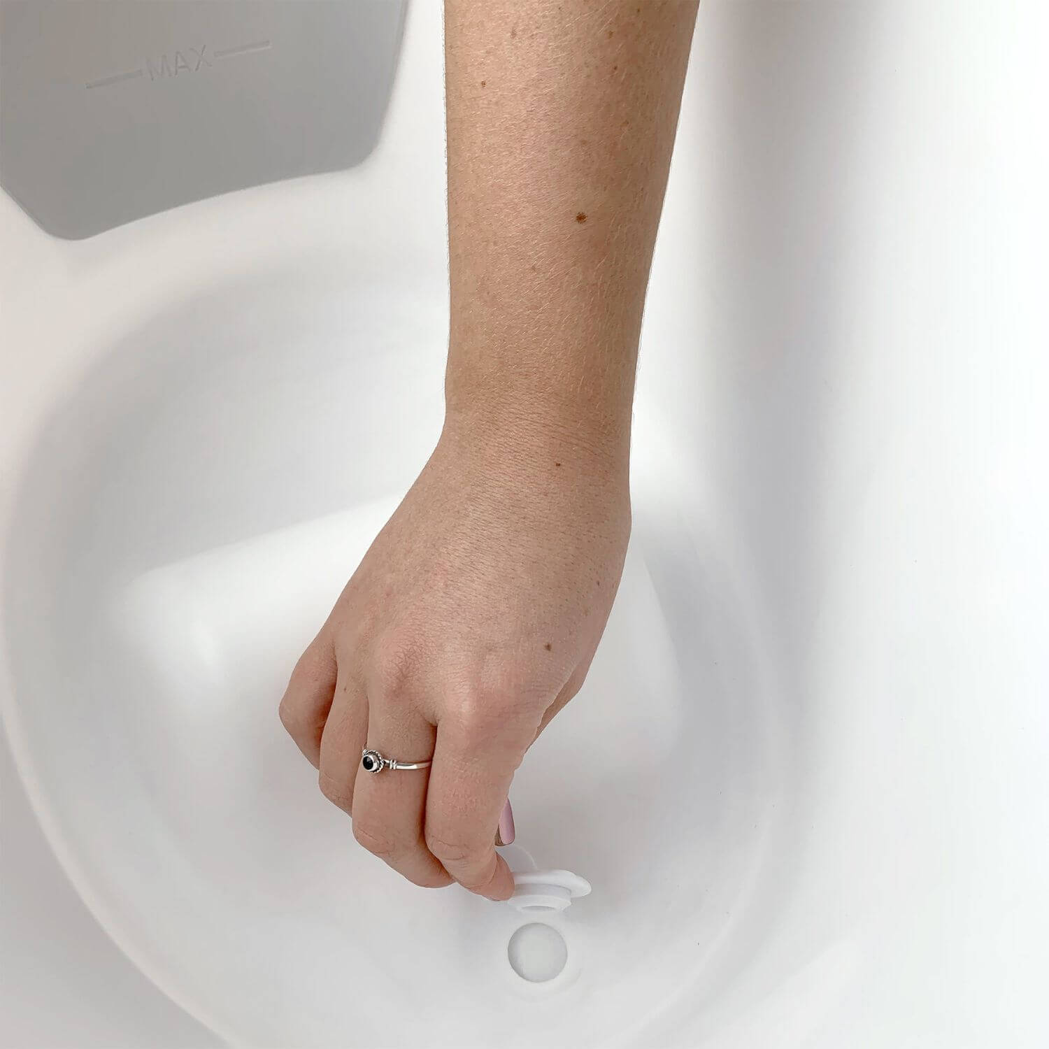 Hand with a ring on a white surface
