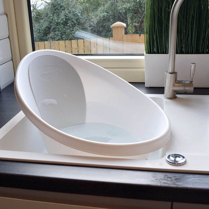 White baby bathtub on a kitchen counter with a window in the background