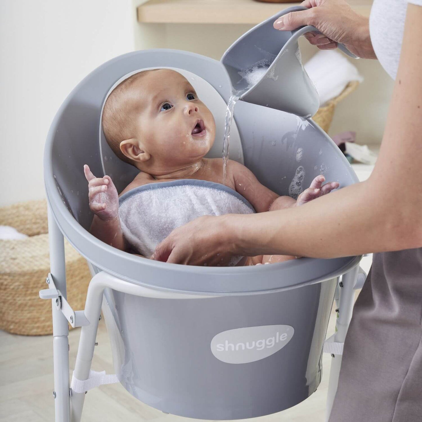 Baby being bathed in a Shnuggle baby bath seat with water being poured over them.
