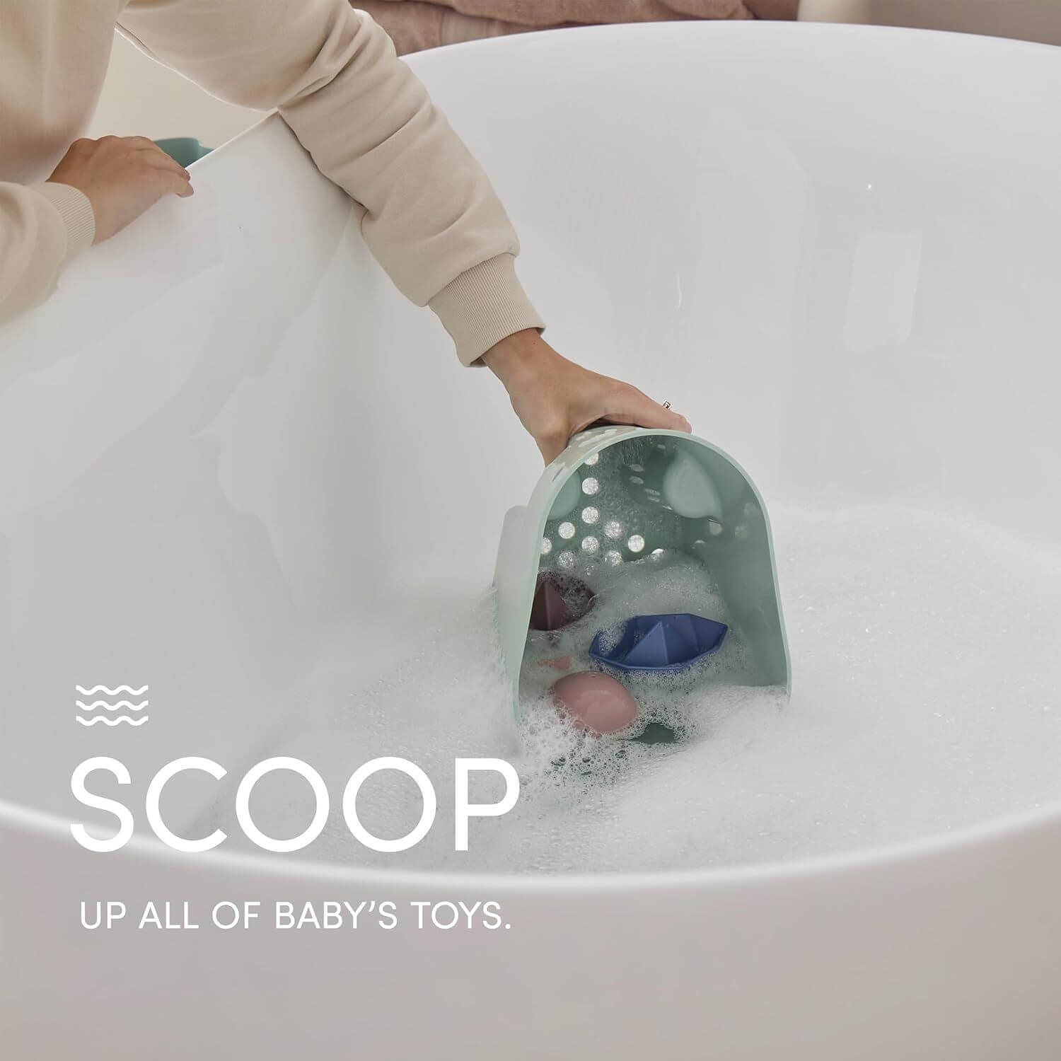 Person scooping water with a green toy from a bathtub, with text 'SCOOP UP ALL OF BABY'S TOYS.'