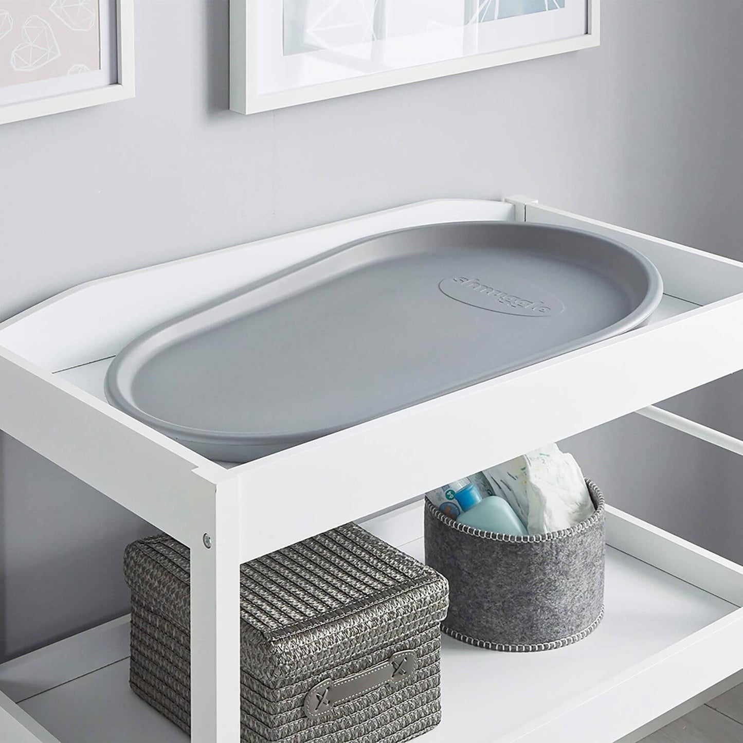 White changing table with gray plastic tray in a nursery setting