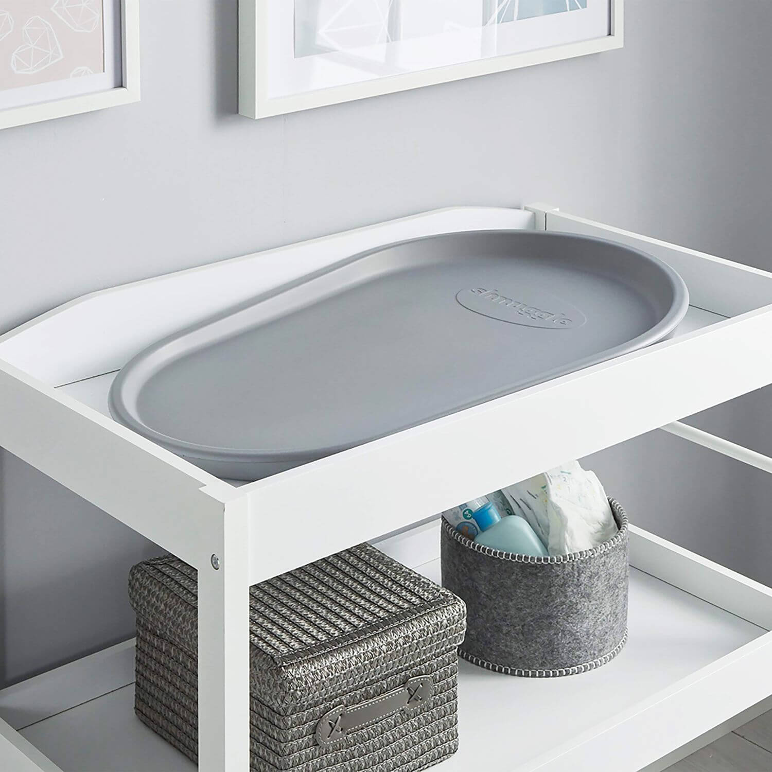 White changing table with gray plastic tray in a nursery setting