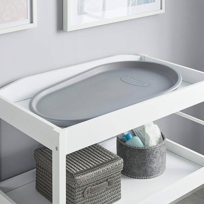 White changing table with gray plastic tray in a nursery setting