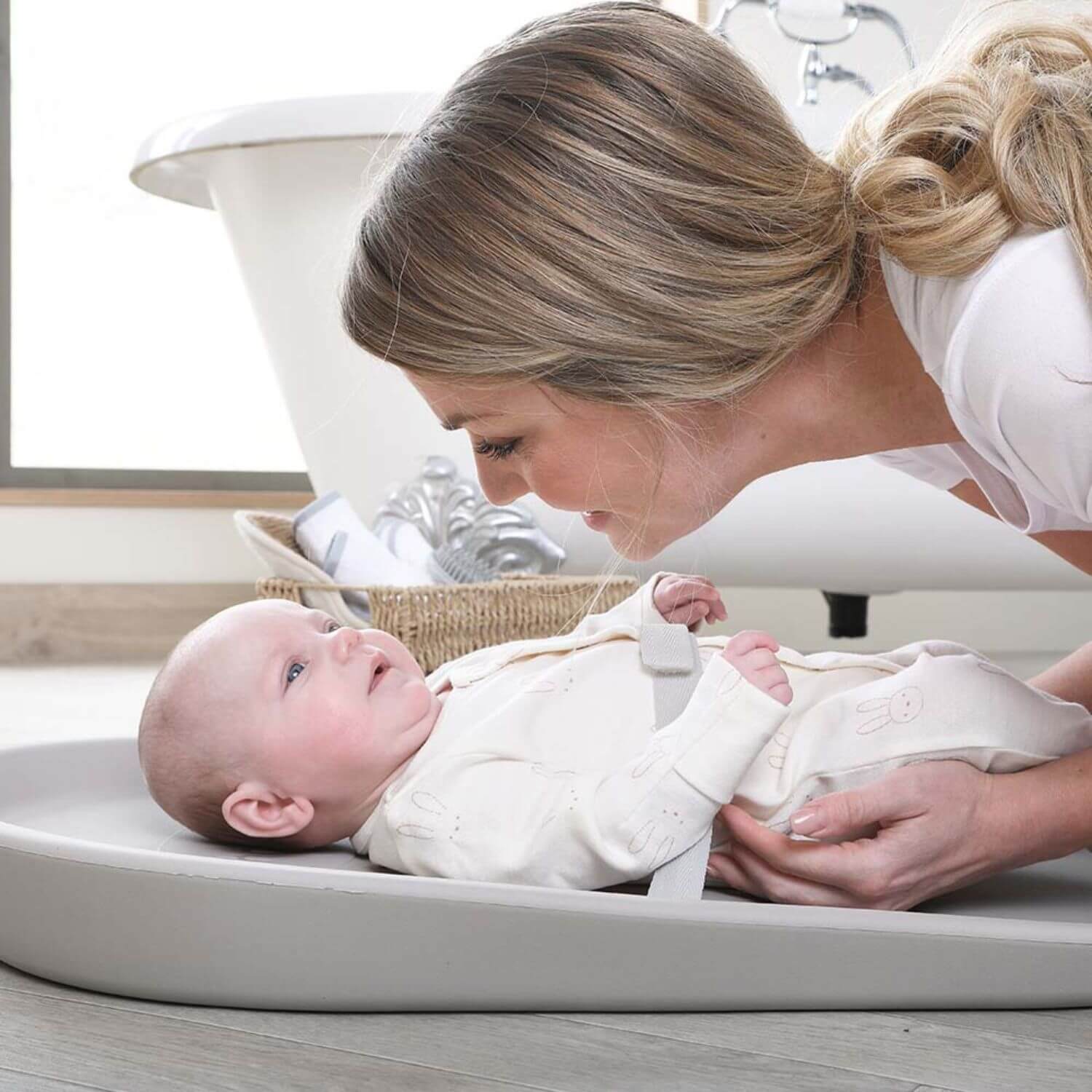 Woman holding a baby in a changing table in a bathroom setting