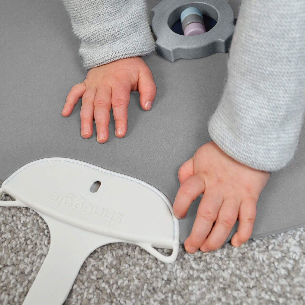 A close-up of a child's hands on Shnuggle Portable Changing & Play Mat