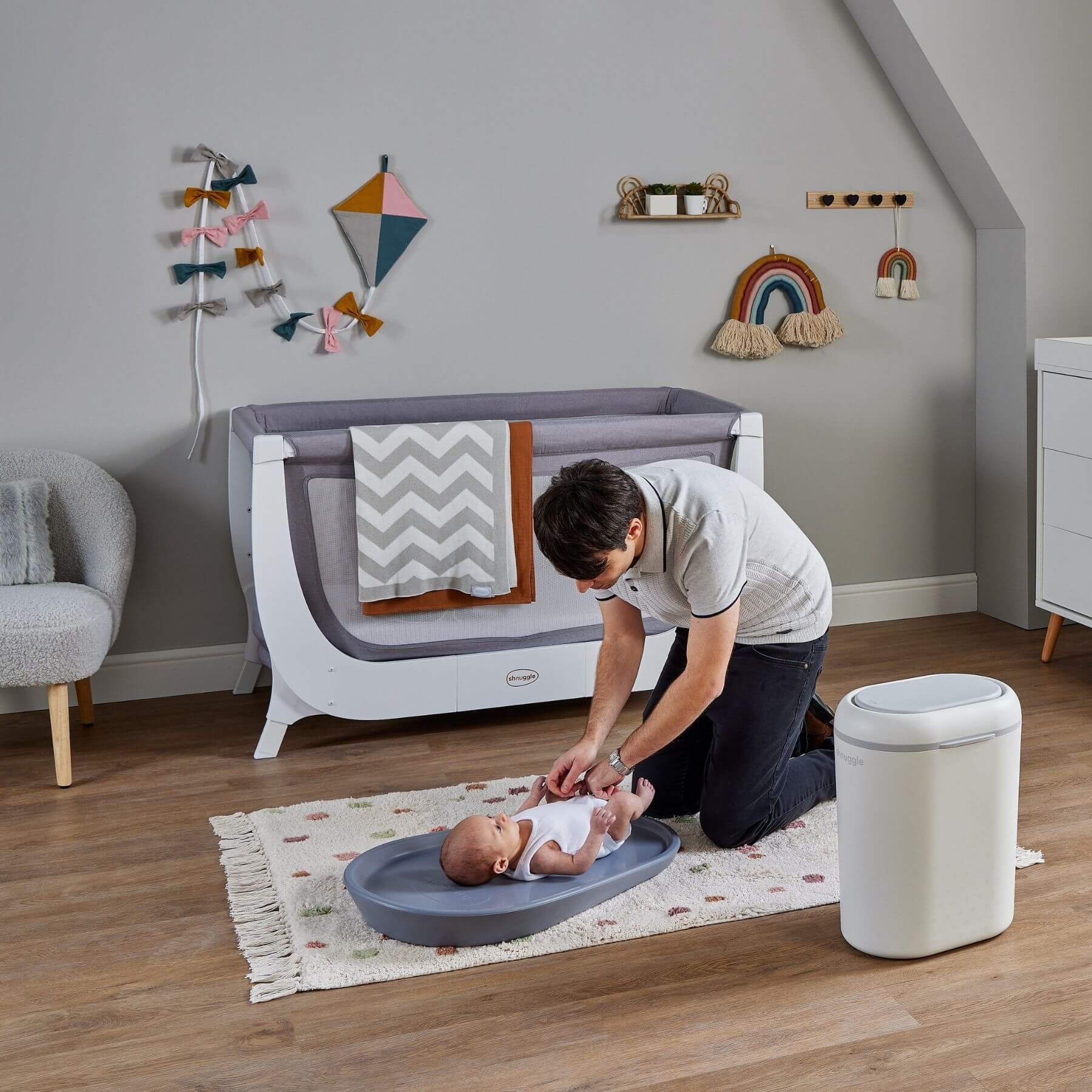 Woman changing a baby on a changing table in a nursery with decorative elements.