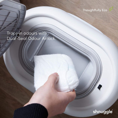 Person placing a white towel into Shnuggle Eco-Touch Nappy Bin Diaper Pail - White with text about odour control.