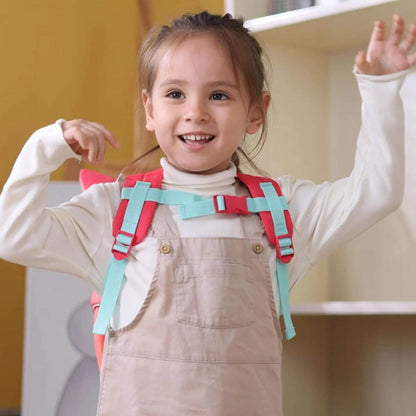 Child wearing a colorful backpack with arms raised indoors.