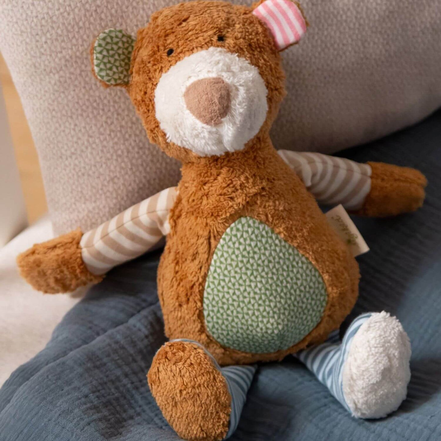 sigikid Organic Bear Plush Toy, sitting on a blue textured blanket.