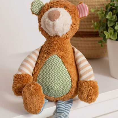sigikid Organic Bear Plush Toy, sitting on a white surface in a softly styled indoor setting.
