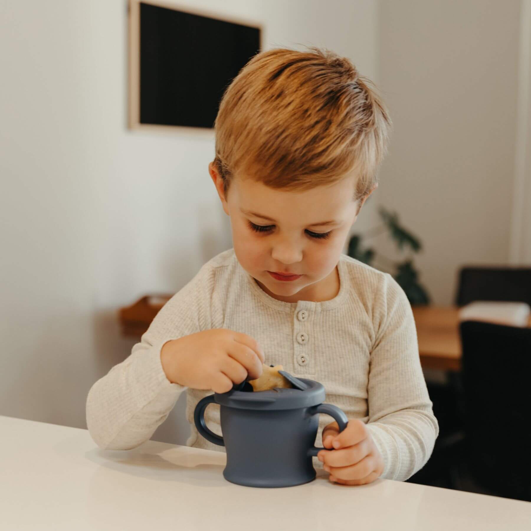 Child playing with Haakaa Silicone Sip-N-Snack Cup 8 oz indoors
