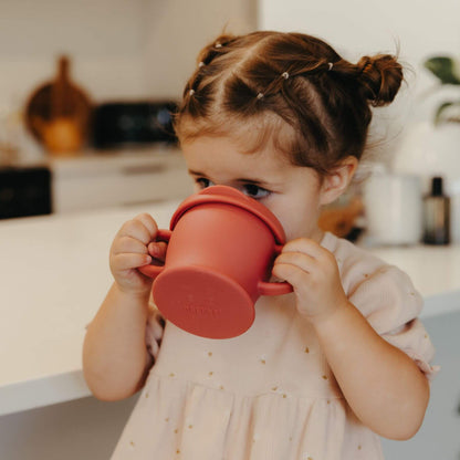 Child drinking from Haakaa Silicone Sip-N-Snack Cup 8 oz in a kitchen setting
