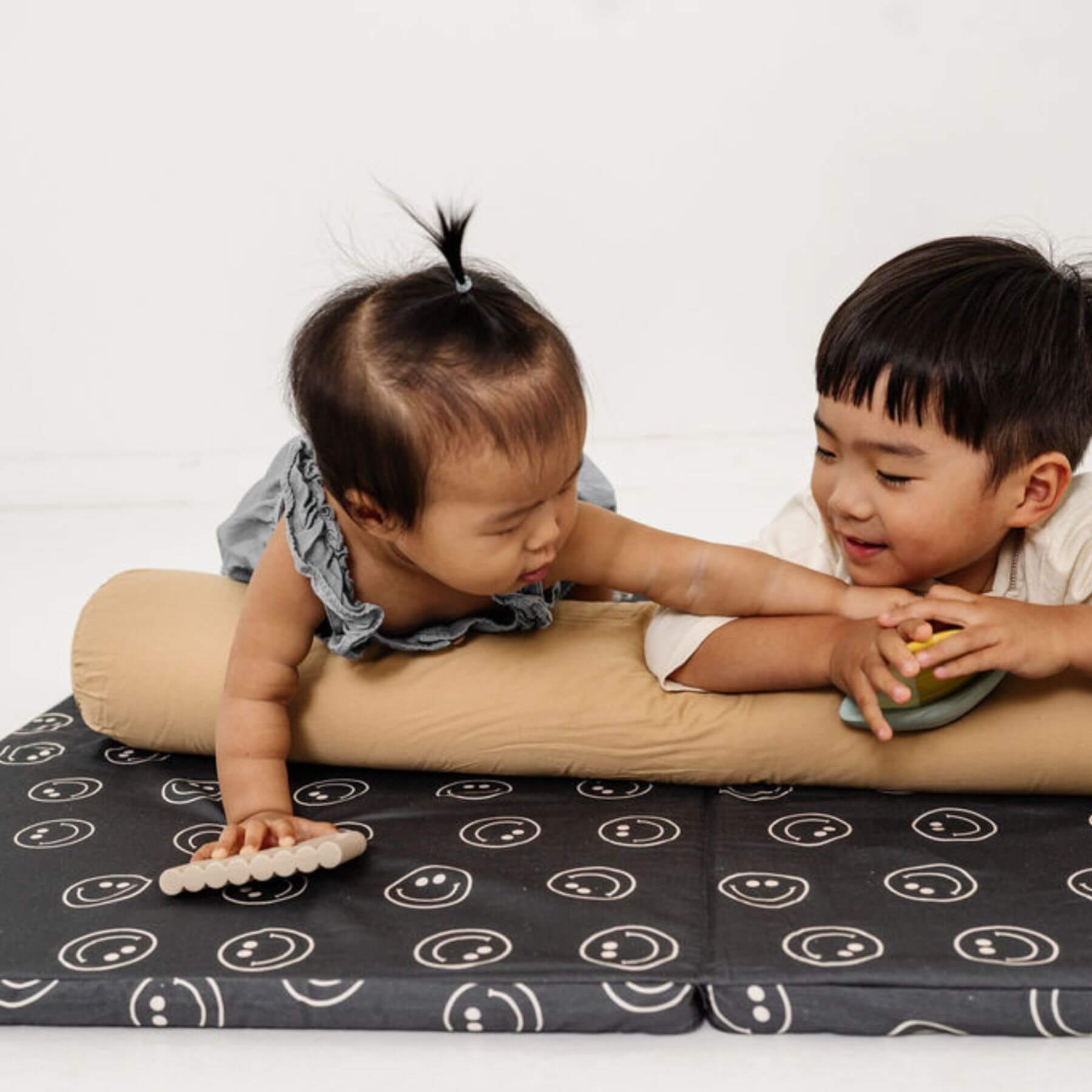 Two children playing on a cushion with a white background