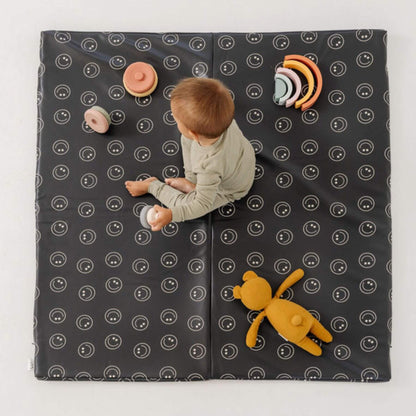 Child playing on Toki Kids Smiles Vegan Leather Mat with white patterns and colorful toys.