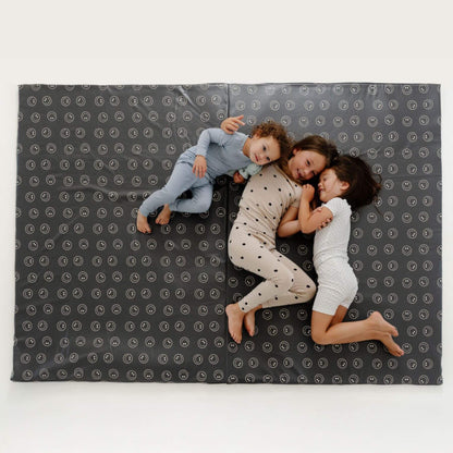Three children lying on Toki Kids Smiles Vegan Leather Mat