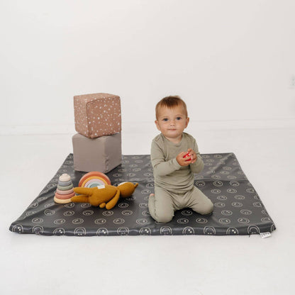 Child playing on a mat with toys on a white background