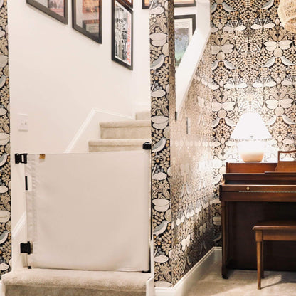 Staircase with a baby gate, patterned walls, and a piano in a home setting.