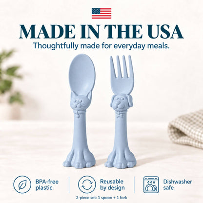 Spoon la la Toddler Utensils — 2-Pack - Blue, shown on a light neutral background with text reading 'MADE IN THE USA' and feature icons for BPA-free plastic, reusable by design, and dishwasher safe.