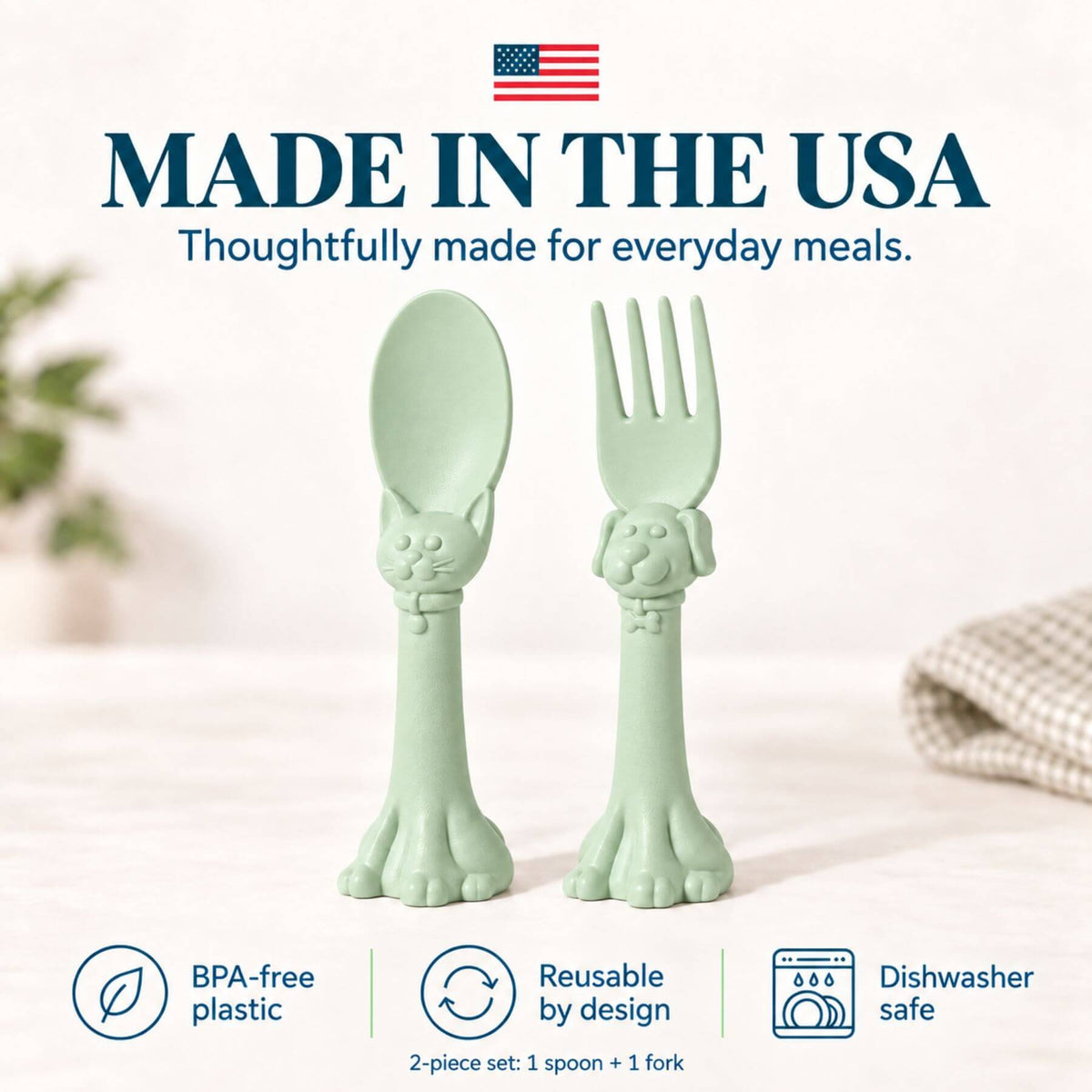 Spoon la la Toddler Utensils — 2-Pack - Green, shaped like cat heads with paw handles. The image features a clean, bright background with text overlays highlighting 'Made in the USA', 'BPA-free plastic', 'Reusable by design', and 'Dishwasher safe'.
