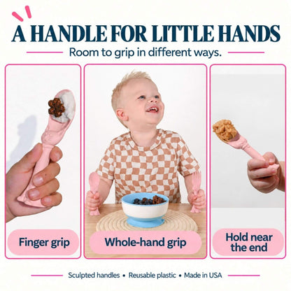 Promotional graphic for Spoon la la Toddler Utensils — 2-Pack - Pink, showing three usage scenarios: finger grip, whole-hand grip, and holding near the end. A smiling toddler is shown in the center holding the spoon handle over a bowl of cereal.