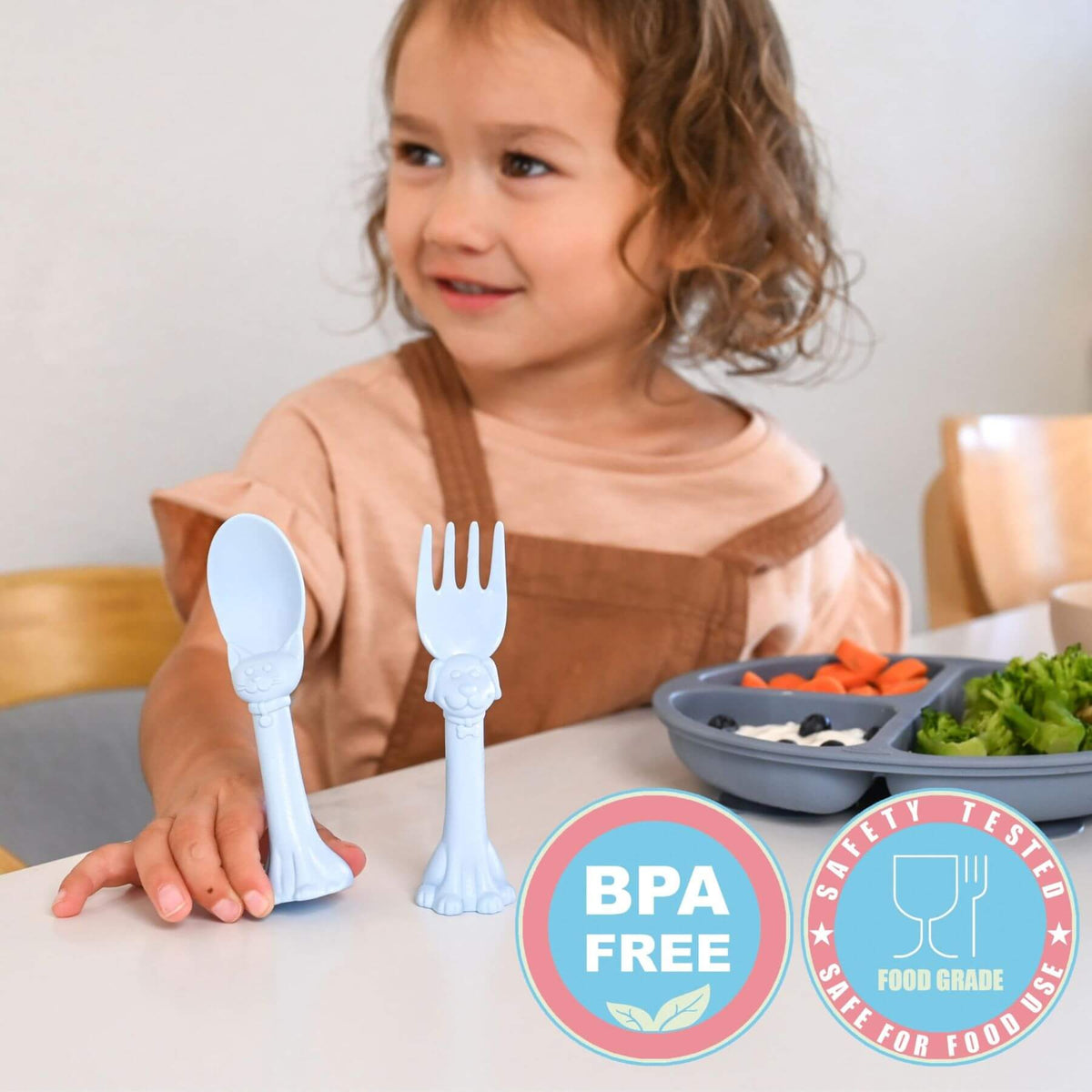 Child with BPA-free plastic fork and spoon at a table with food.