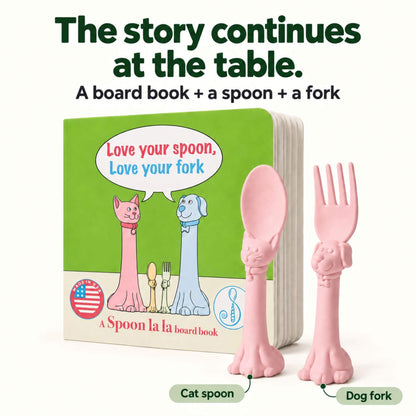 A children's board book and matching utensil set. The set includes a green board book with cartoon cat and dog figures and the text 'Love your spoon, Love your fork,' plus a pink cat-shaped spoon and a pink dog-shaped fork.