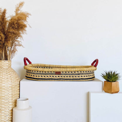 Plum+Sparrow Spring Sparrow Changing Basket on a white surface, surrounded by decorative items.