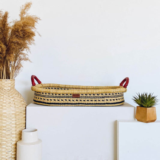 Plum+Sparrow Spring Sparrow Changing Basket on a white surface, surrounded by decorative items.