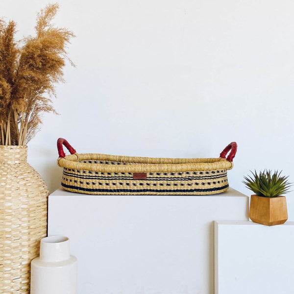 Plum+Sparrow Spring Sparrow Changing Basket on a white surface, surrounded by decorative items.