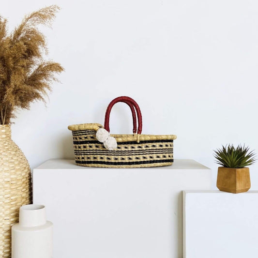 Plum+Sparrow Spring Sparrow Mini Moses Basket on a white surface, surrounded by decorative items.