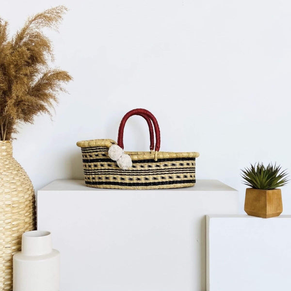 Plum+Sparrow Spring Sparrow Mini Moses Basket on a white surface, surrounded by decorative items.