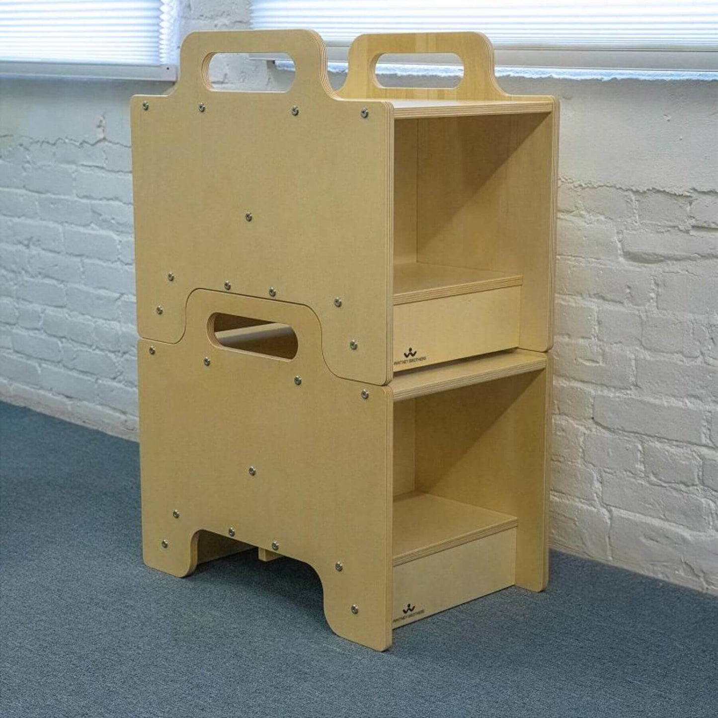 2 Whitney Brothers Stack-Able™ Seat against a white brick wall.