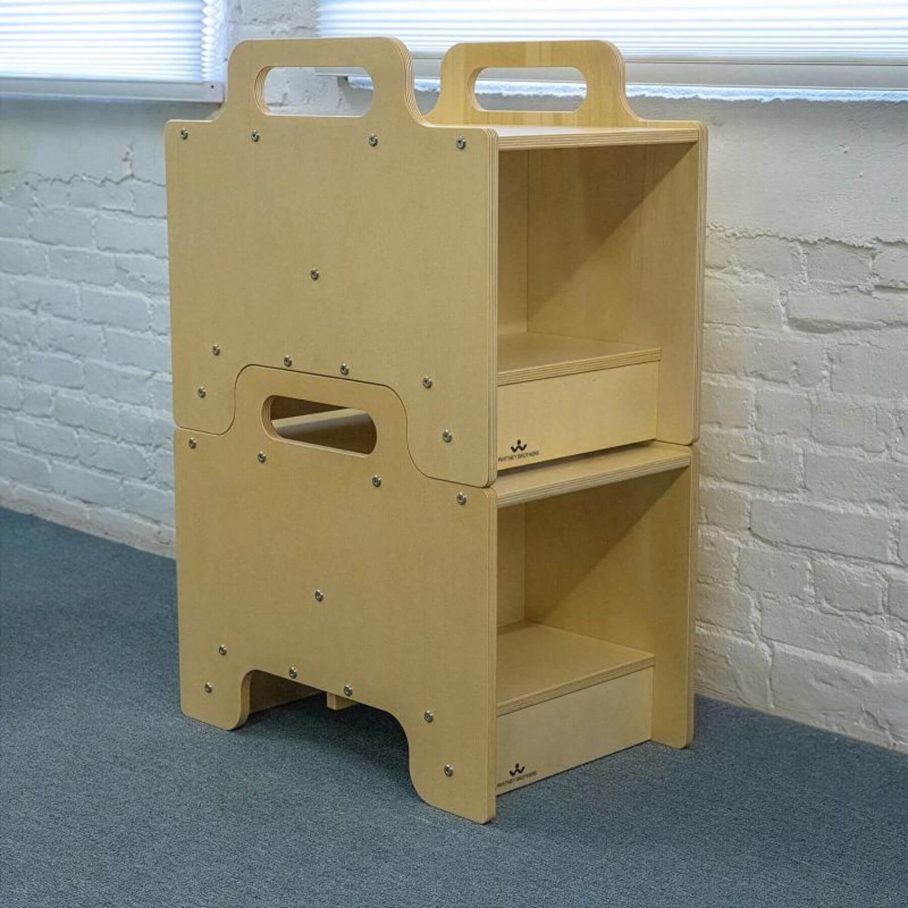 2 Whitney Brothers Stack-Able™ Seat against a white brick wall.