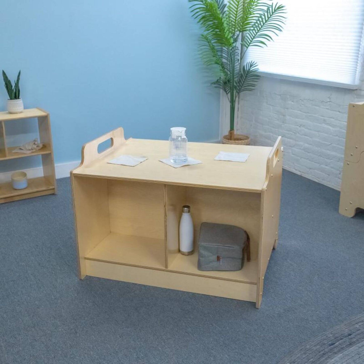 Stack-Able™ Table with shelves in a room with a blue wall and plants.