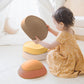 Child playing with Tiny Land® Stepping Stones - Sunset Hues on a light-colored surface